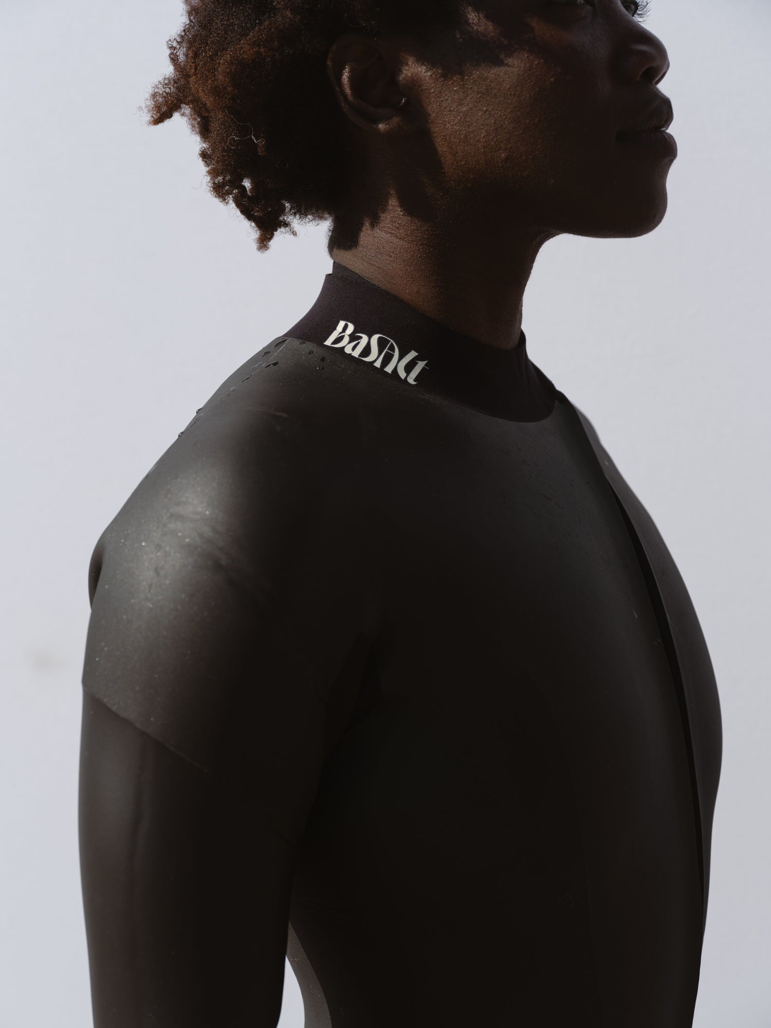 Detail of woman in a Basalt 4/3mm smoothskin wetsuit with curved front zip and subtle Basalt logo